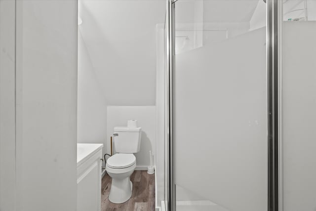 bathroom featuring an enclosed shower, vaulted ceiling, hardwood / wood-style floors, vanity, and toilet