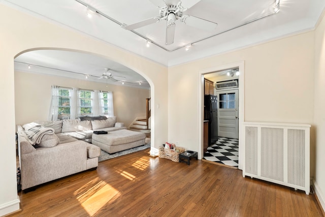 living room featuring rail lighting, radiator, hardwood / wood-style floors, and ceiling fan