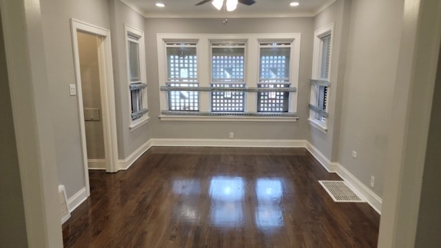 empty room featuring crown molding, dark hardwood / wood-style flooring, and ceiling fan