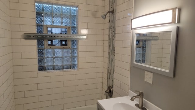 bathroom with a tile shower and sink