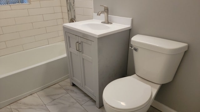 full bathroom featuring vanity, tiled shower / bath combo, and toilet