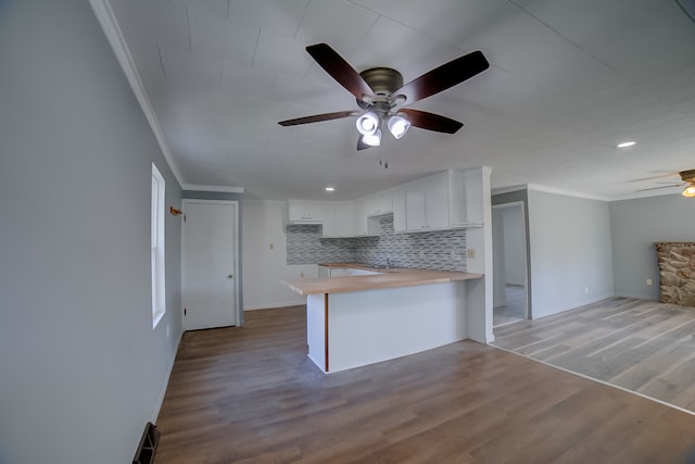 kitchen featuring ceiling fan, white cabinets, kitchen peninsula, hardwood / wood-style flooring, and decorative backsplash