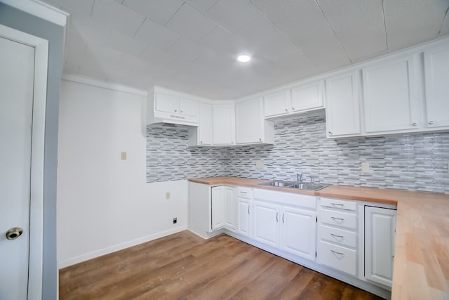 kitchen with sink, white cabinets, backsplash, hardwood / wood-style floors, and butcher block countertops