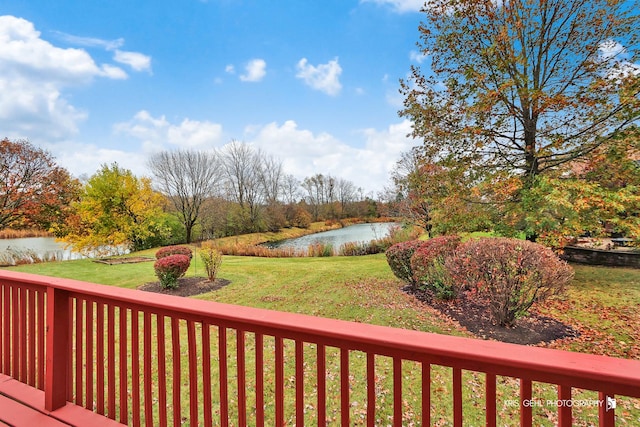 wooden terrace featuring a lawn and a water view