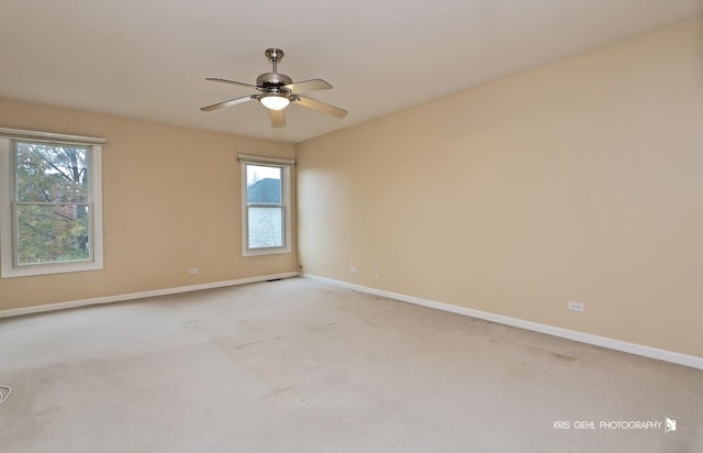 carpeted empty room with ceiling fan and plenty of natural light