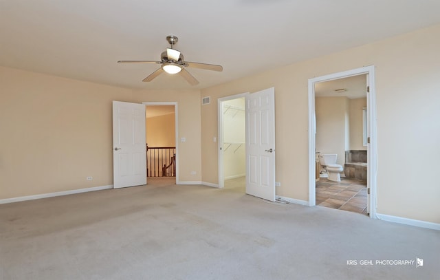 unfurnished bedroom featuring ensuite bathroom, ceiling fan, a spacious closet, light colored carpet, and a closet