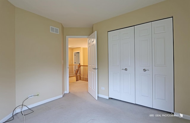 unfurnished bedroom with light carpet and a closet