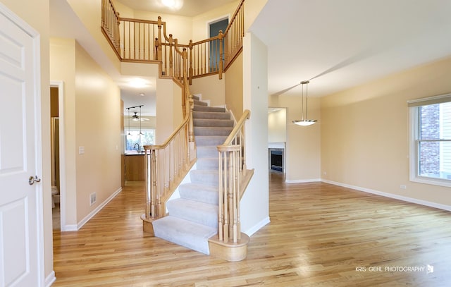 stairway with hardwood / wood-style floors, a towering ceiling, and ceiling fan