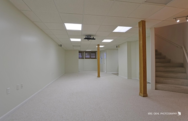 basement featuring a drop ceiling and light colored carpet