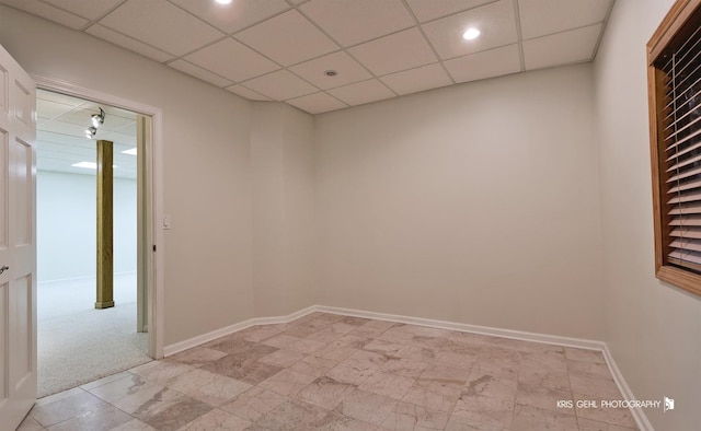 empty room featuring a paneled ceiling and light colored carpet