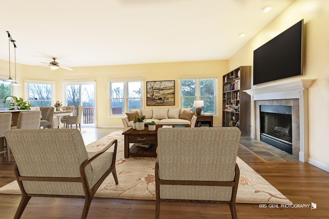 living room with hardwood / wood-style flooring, ceiling fan, sink, and a tile fireplace