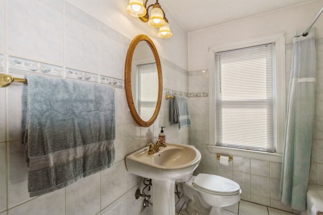 bathroom with tile walls, sink, a shower with curtain, tile patterned floors, and toilet