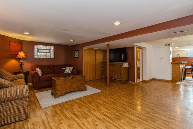 living room with light hardwood / wood-style floors and bar area