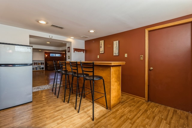 kitchen with light hardwood / wood-style flooring, white fridge, and a breakfast bar