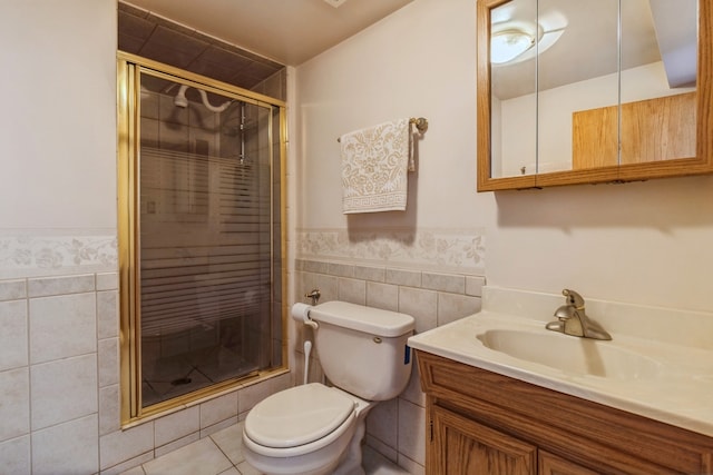 bathroom featuring vanity, tile patterned floors, tile walls, toilet, and a shower with door