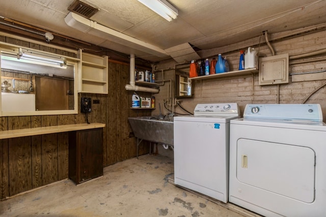 laundry area with wood walls and separate washer and dryer