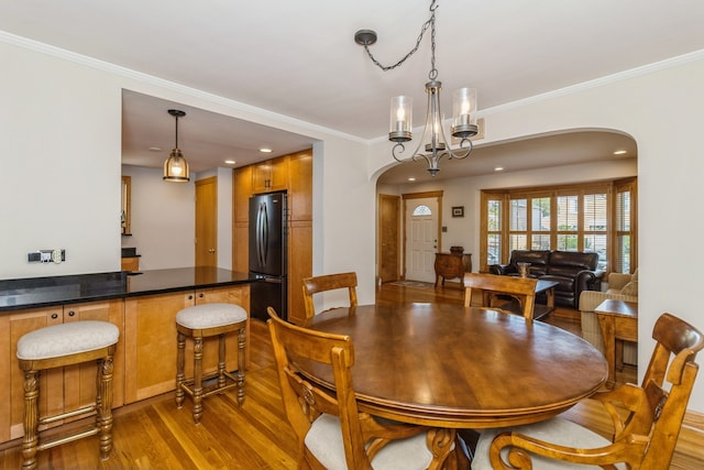 dining area featuring an inviting chandelier, crown molding, and light hardwood / wood-style floors