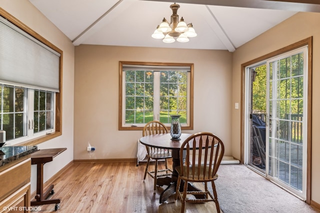 dining area with an inviting chandelier, light wood-type flooring, and vaulted ceiling