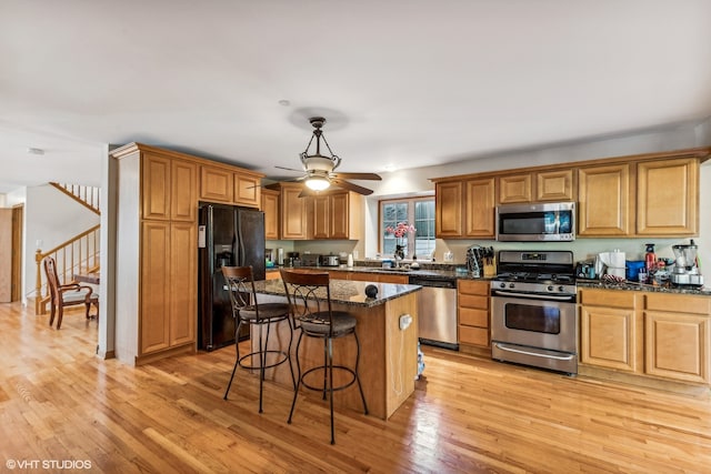 kitchen featuring light hardwood / wood-style floors, dark stone countertops, and appliances with stainless steel finishes