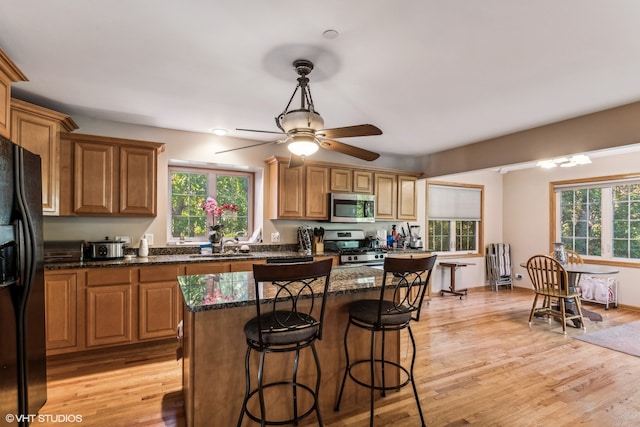 kitchen featuring a kitchen island, appliances with stainless steel finishes, a healthy amount of sunlight, and light hardwood / wood-style flooring