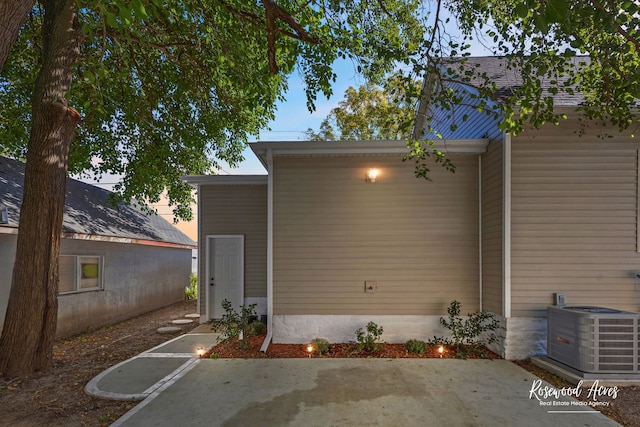 back house at dusk featuring central AC unit and a patio area