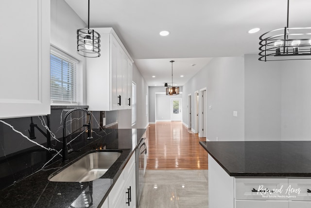 kitchen with hanging light fixtures, sink, white cabinetry, dark stone countertops, and decorative backsplash