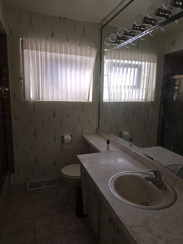 bathroom with toilet, a shower, tile patterned flooring, and vanity