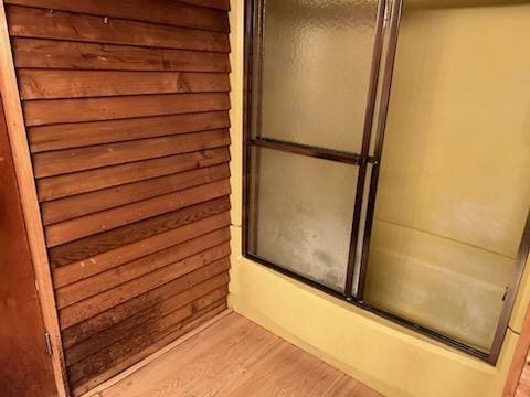 bathroom featuring bath / shower combo with glass door and hardwood / wood-style floors