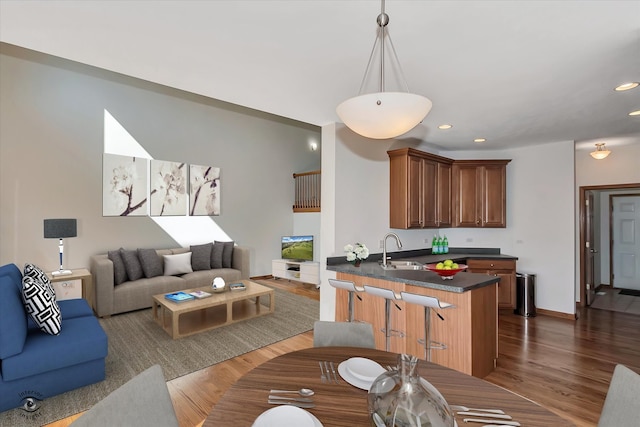 kitchen featuring dark hardwood / wood-style flooring, kitchen peninsula, sink, and pendant lighting