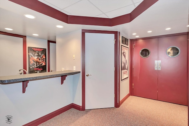 hallway featuring a drop ceiling and light colored carpet