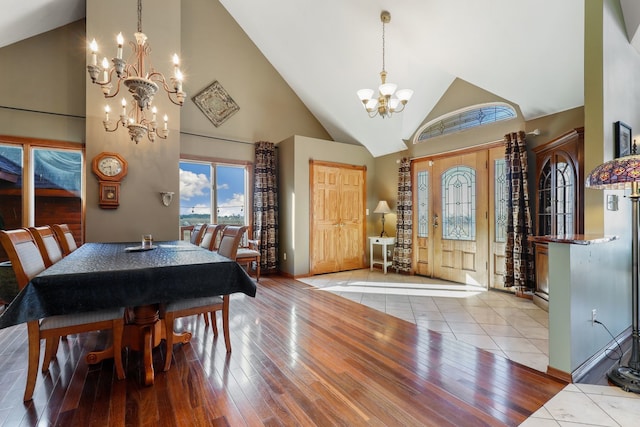 dining area featuring light wood-type flooring, a chandelier, and high vaulted ceiling