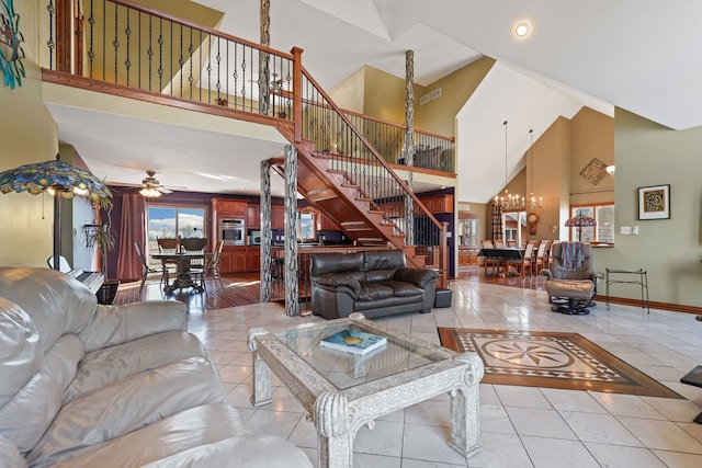 living room featuring ceiling fan with notable chandelier, a towering ceiling, and light tile patterned floors