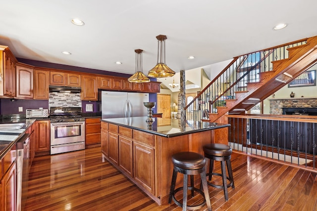 kitchen with hanging light fixtures, a kitchen island, dark hardwood / wood-style flooring, and stainless steel appliances