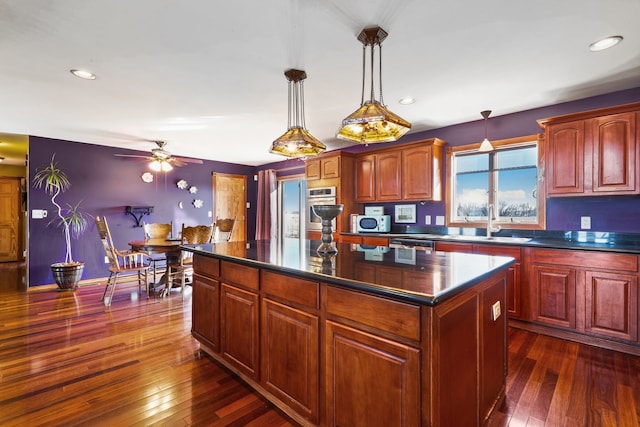 kitchen with ceiling fan, pendant lighting, sink, a kitchen island, and dark hardwood / wood-style floors