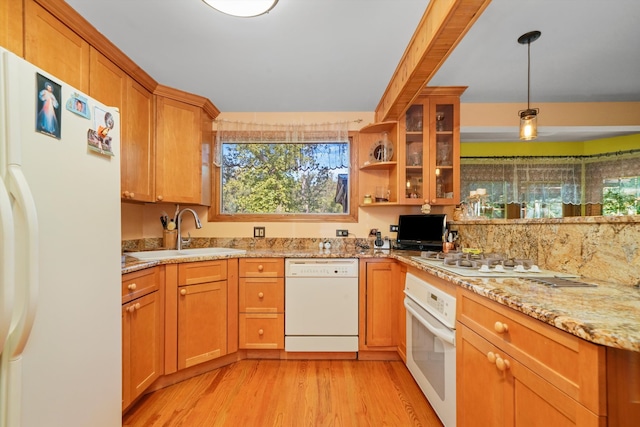 kitchen with light stone counters, white appliances, pendant lighting, light wood-type flooring, and sink