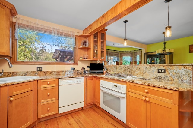 kitchen featuring hanging light fixtures, sink, white appliances, light stone countertops, and light hardwood / wood-style floors