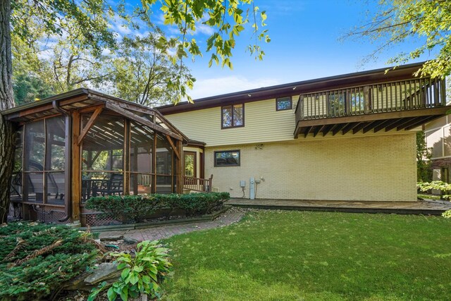 back of house featuring a sunroom, a balcony, and a yard