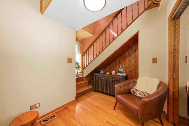 sitting room featuring light wood-type flooring and wooden walls