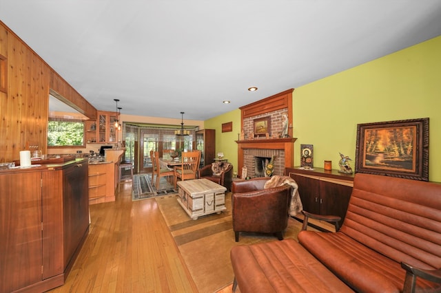 living room featuring wooden walls, light wood-type flooring, and a fireplace