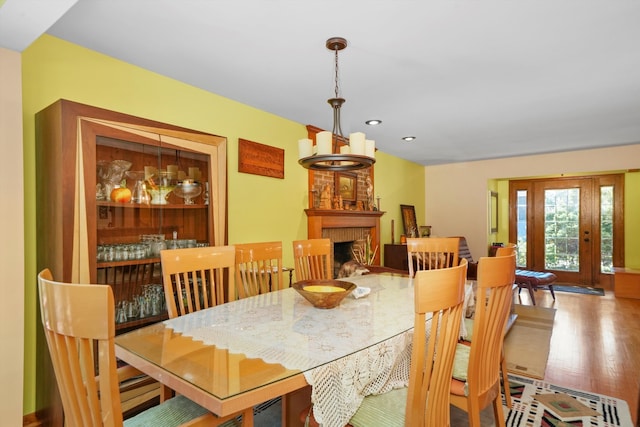 dining area featuring an inviting chandelier, wood-type flooring, and a fireplace