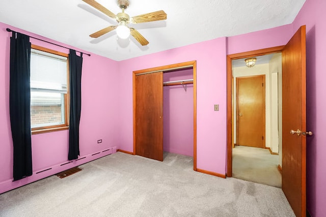 unfurnished bedroom featuring light carpet, a baseboard heating unit, a closet, and ceiling fan