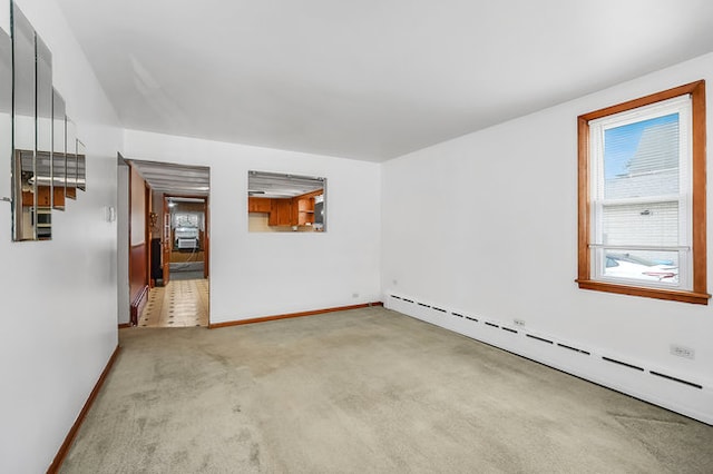 carpeted spare room featuring a baseboard heating unit