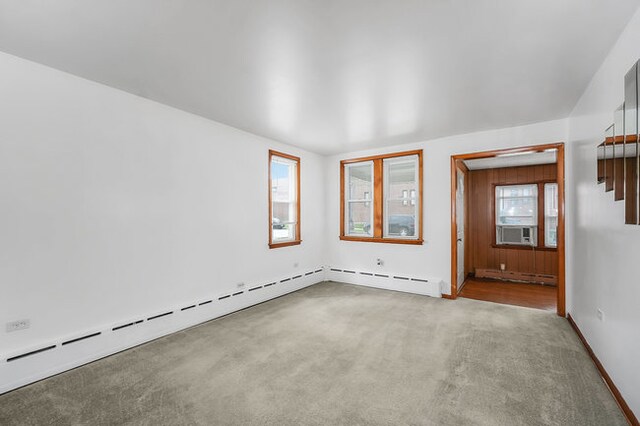 carpeted spare room featuring cooling unit and a baseboard heating unit