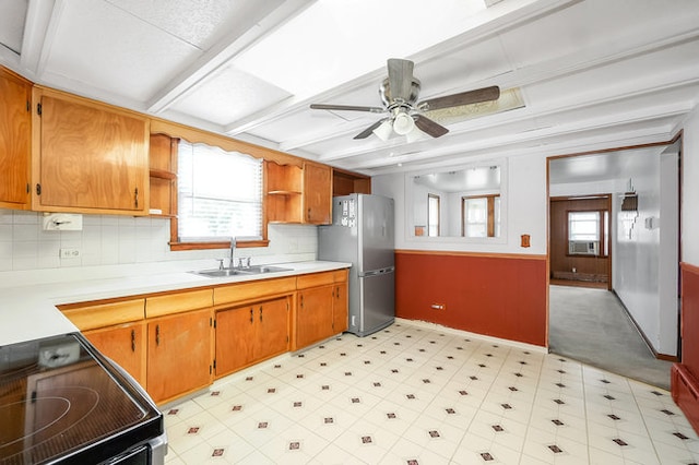 kitchen featuring range, sink, stainless steel fridge, and a wealth of natural light