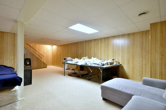 bedroom with wooden walls, a drop ceiling, and carpet