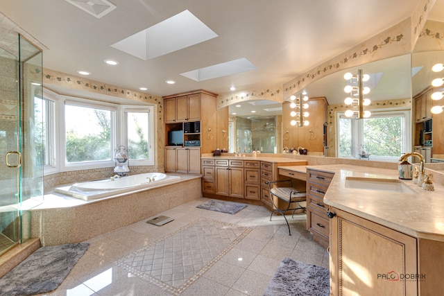 bathroom with a skylight, vanity, plus walk in shower, and a healthy amount of sunlight