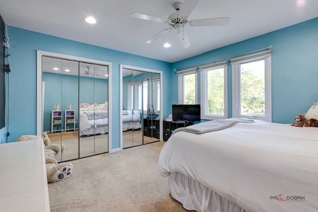 bedroom featuring multiple closets, ceiling fan, and light colored carpet