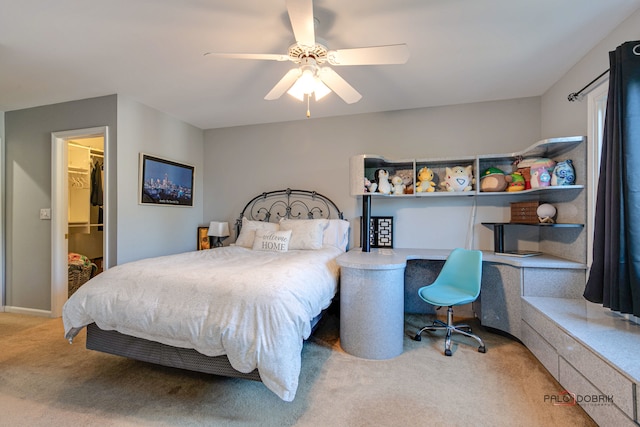 carpeted bedroom with built in desk, a closet, a walk in closet, and ceiling fan