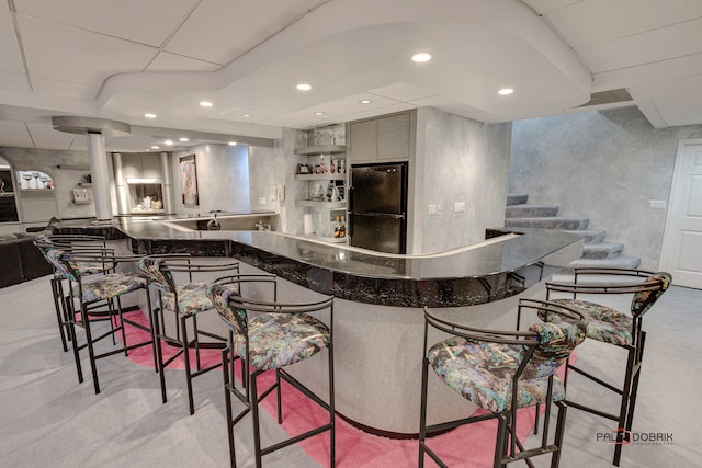 bar featuring gray cabinetry and black refrigerator