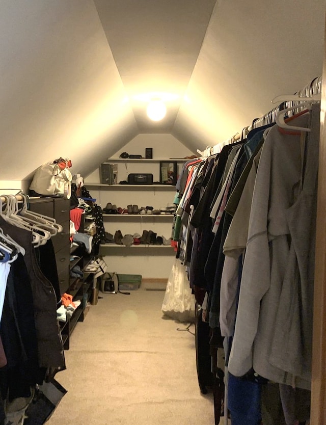 walk in closet with lofted ceiling and light colored carpet